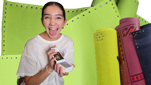 girl holding an open box of yoga mat charms. The background is personalized yoga mats with charms