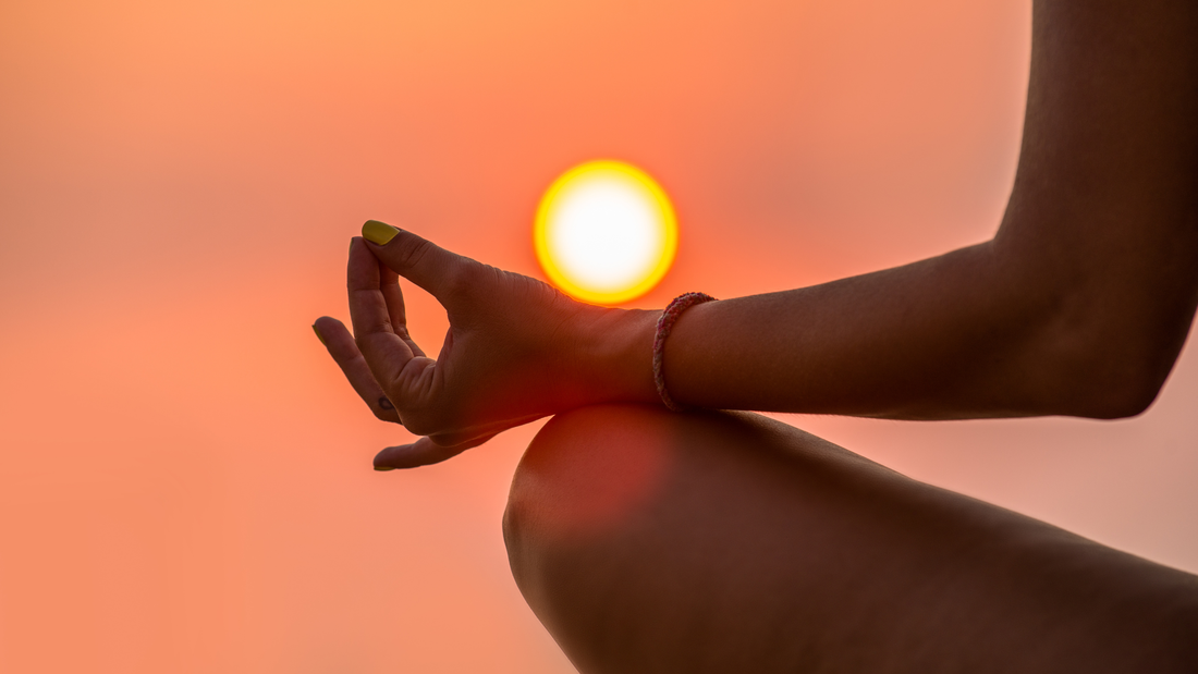 womans hand and knee shown, She is in Lotus Pose meditating, Sunset, yoga