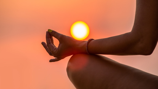 womans hand and knee shown, She is in Lotus Pose meditating, Sunset, yoga
