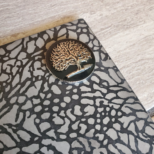 A tree of Life mat marker   installed in a lululemon crackle mat. The yog mat charm is round, slightly domed and has a black enamel background with silver tree